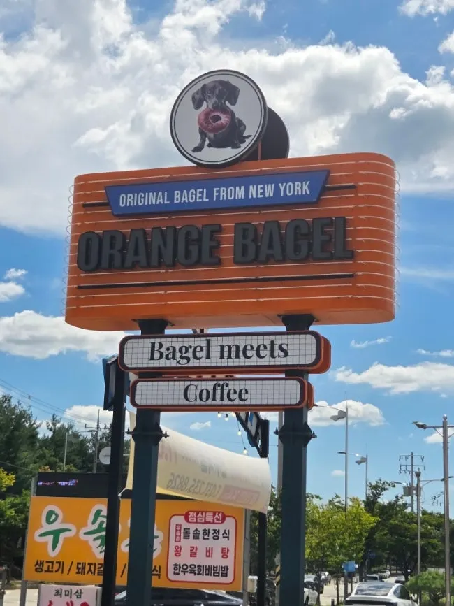 Orange Bagel's exterior with an orange sign on a red brick building