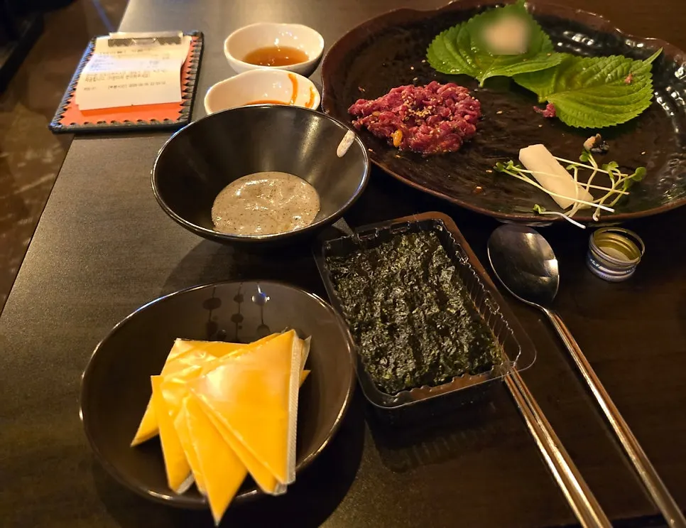 Yukhoe plate garnished with fresh radish sprouts and perilla leaves