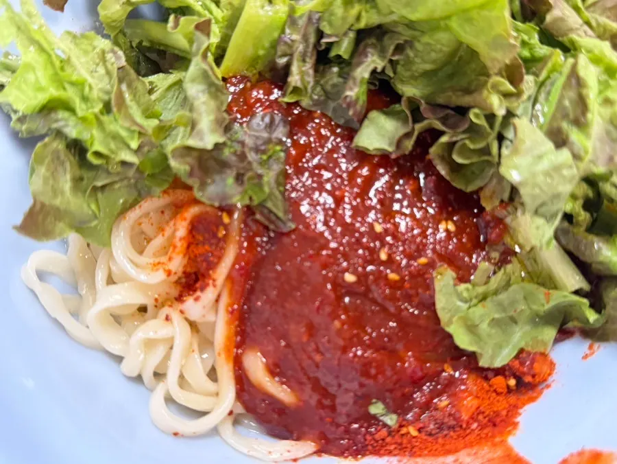 Bibim kalguksu mixed by hand with plastic gloves on