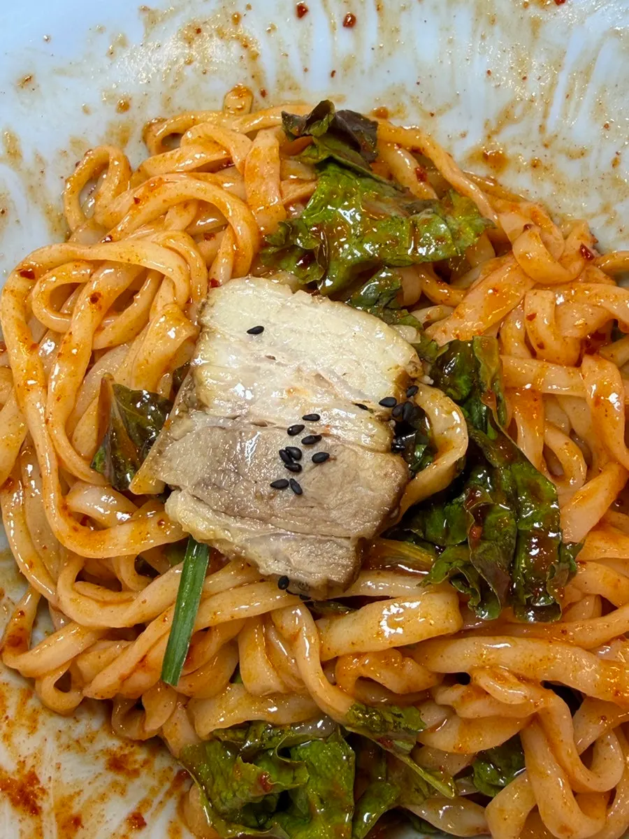 비빔칼국수 면으로 감싼 수육 한 점