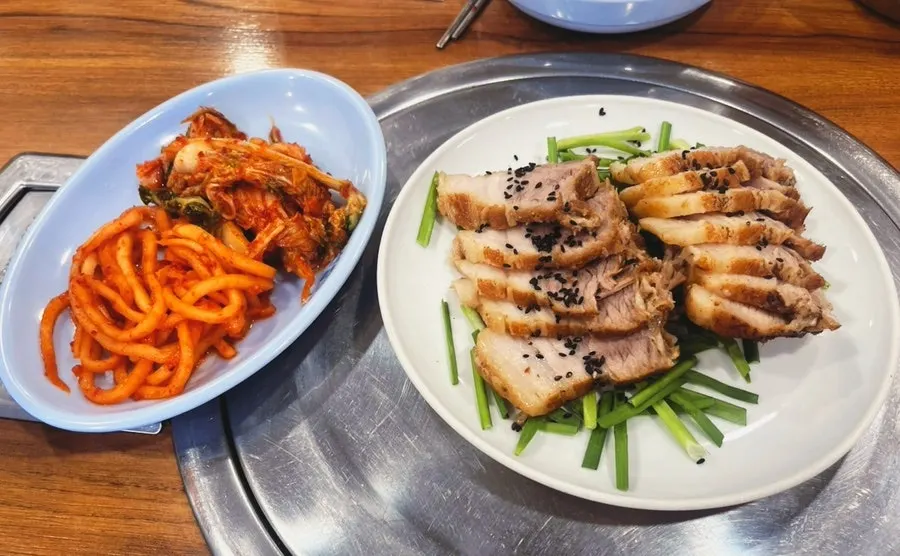 Table spread of basic side dishes including kimchi and radish salad