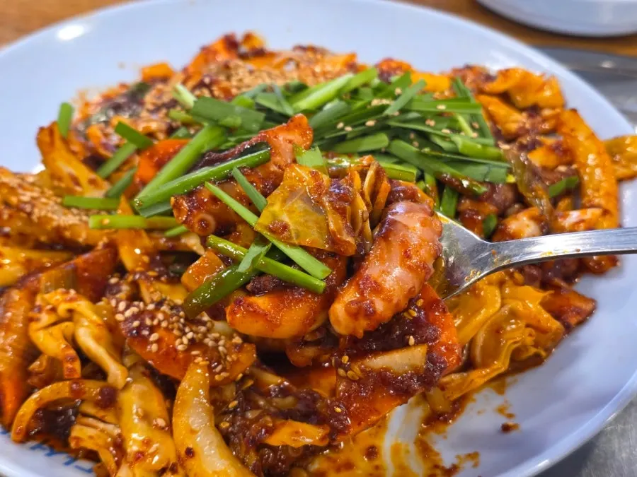 A piece of stir-fried octopus lifted with chopsticks