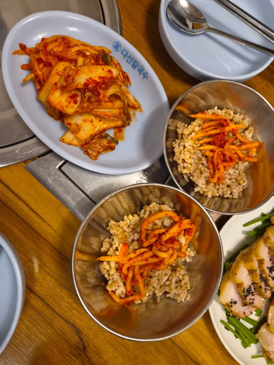 Table setting with barley rice, geotjeori kimchi, and fresh vegetable salad