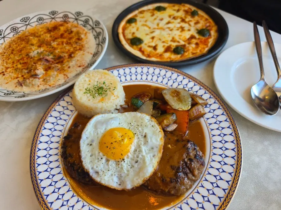 Table spread with pizza, hamburg steak, and gnocchi