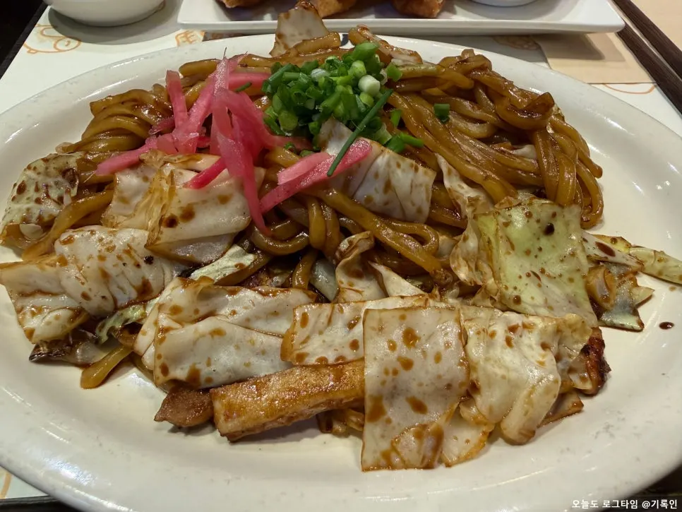 Yakisoba topped with cabbage, pickled ginger, green onion, and squid