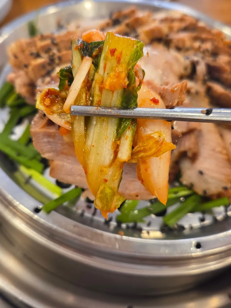 보쌈김치를 올린 수육 한 점