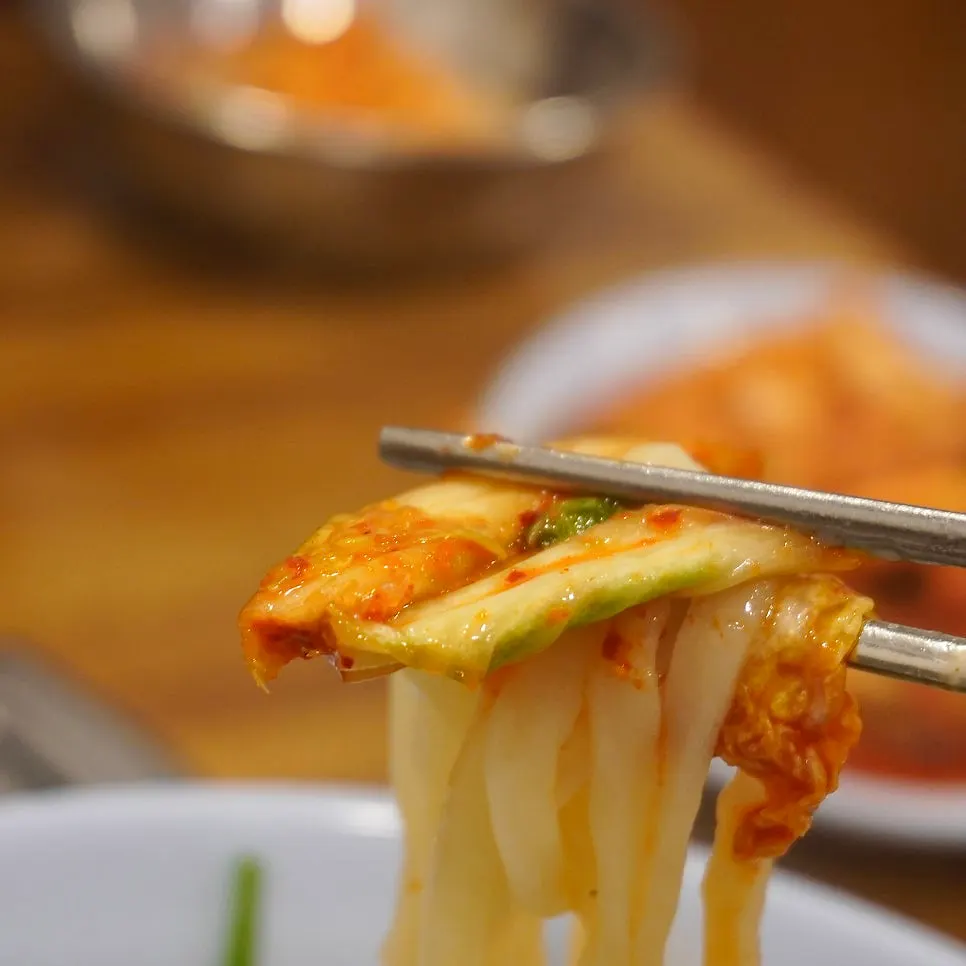 Chewy kalguksu noodles lifted with chopsticks