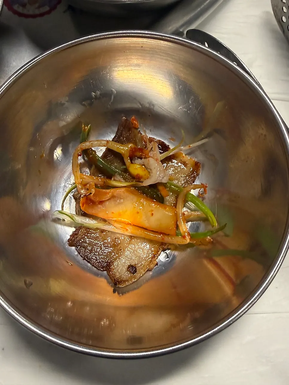 A wrapped bite of naengsam topped with green onion salad