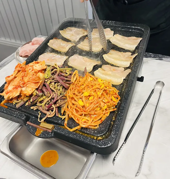 Pork belly and side vegetables placed on the grill