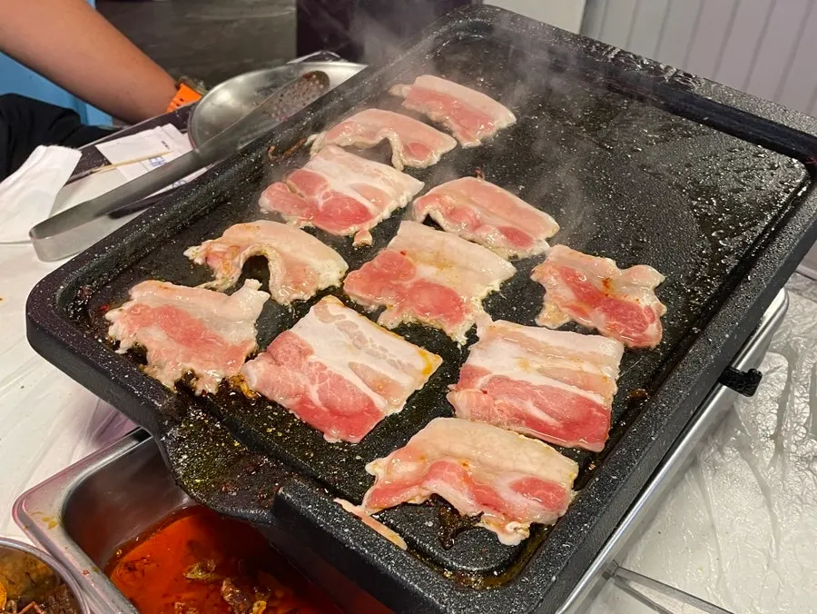 A staff member grilling 4 mm frozen pork belly