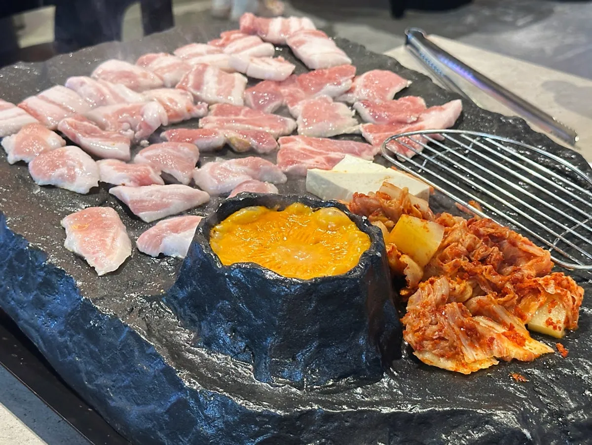 Stone-grilled pork belly dipped in lava fondue cheese