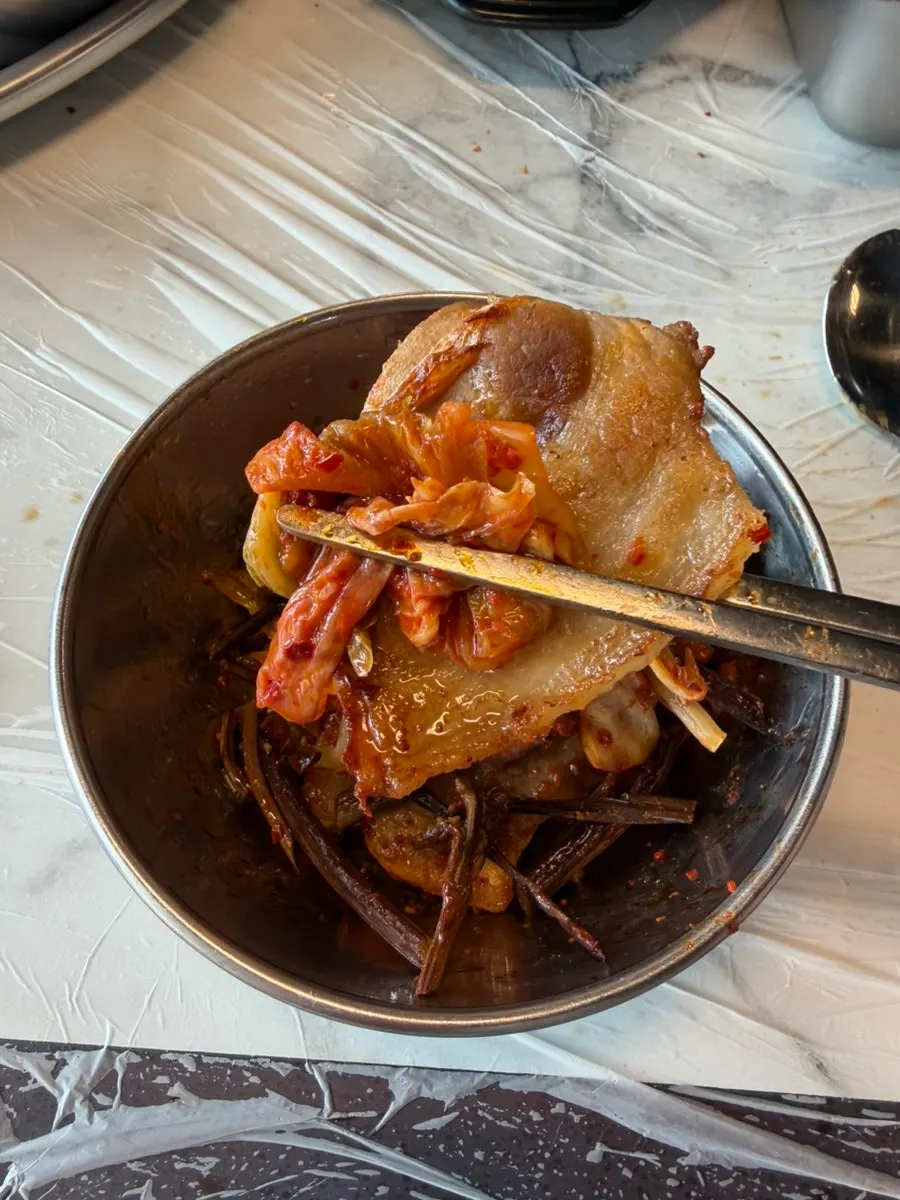 A finished bite of pork belly topped with bracken