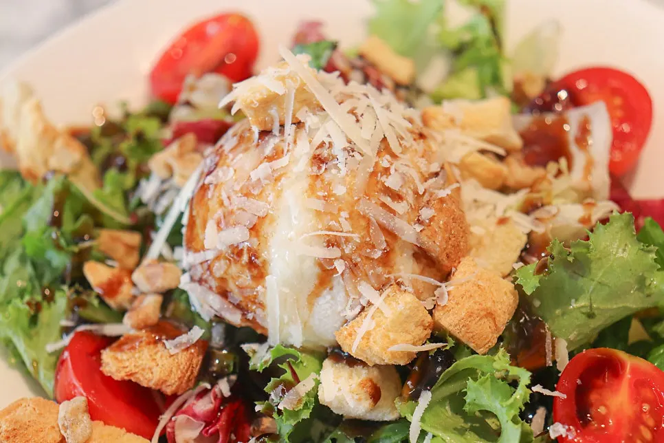 Salad topped with a generous chunk of ricotta cheese