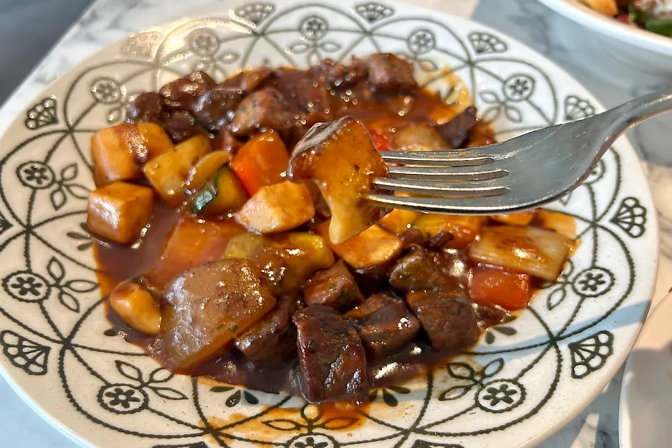 A piece of chop steak meat picked up with a fork