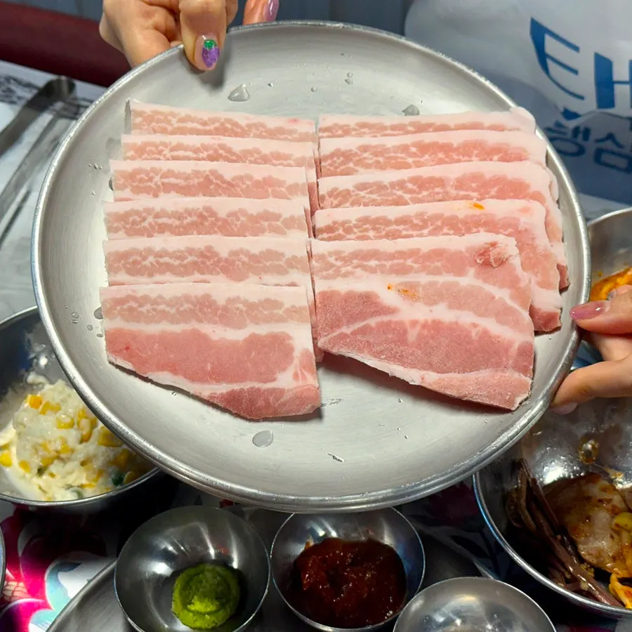 Close-up of a piece of fresh pork belly picked up with chopsticks