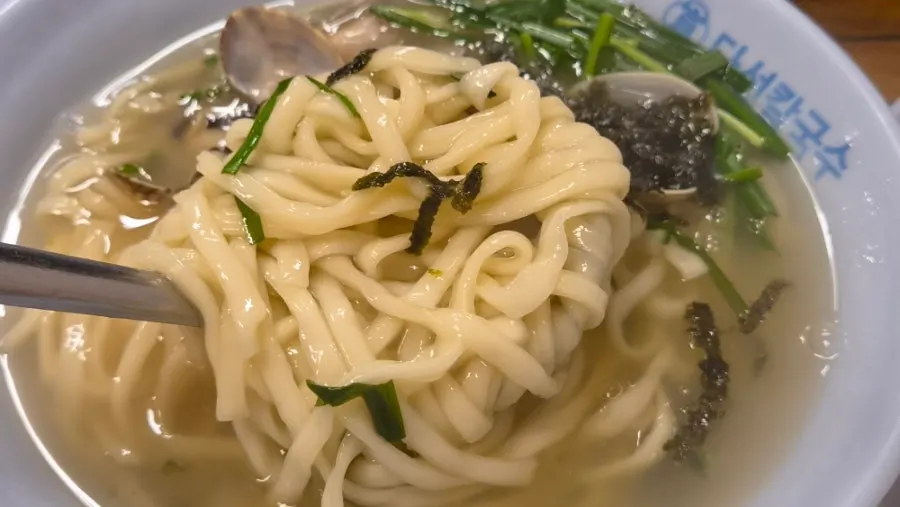 Lifting up noodles from the kalguksu bowl