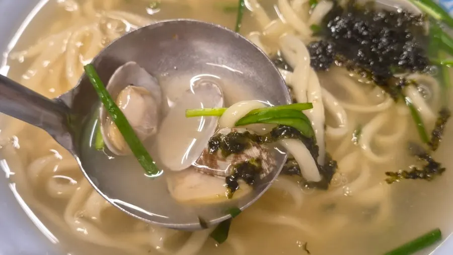 Close-up of kalguksu broth and clams