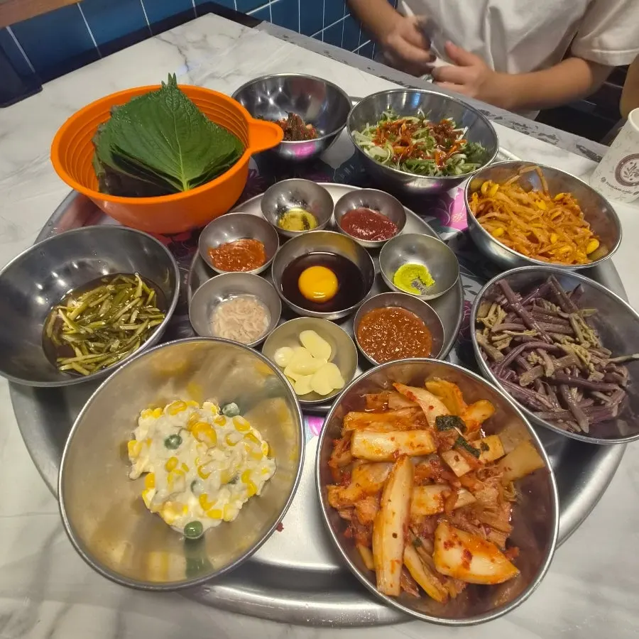 A full spread of side dishes served with frozen pork belly