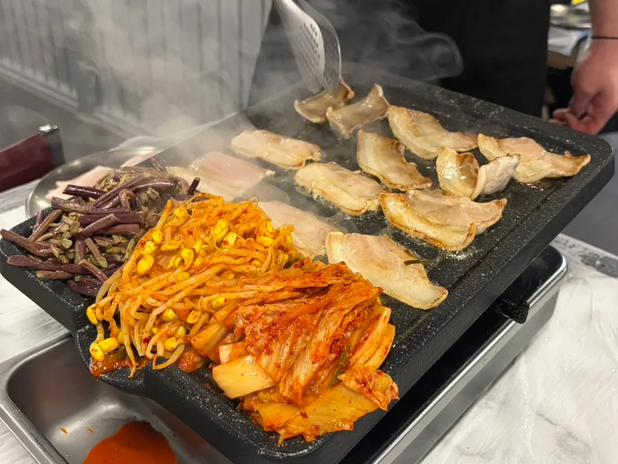 Thin frozen pork belly laid out on the grill