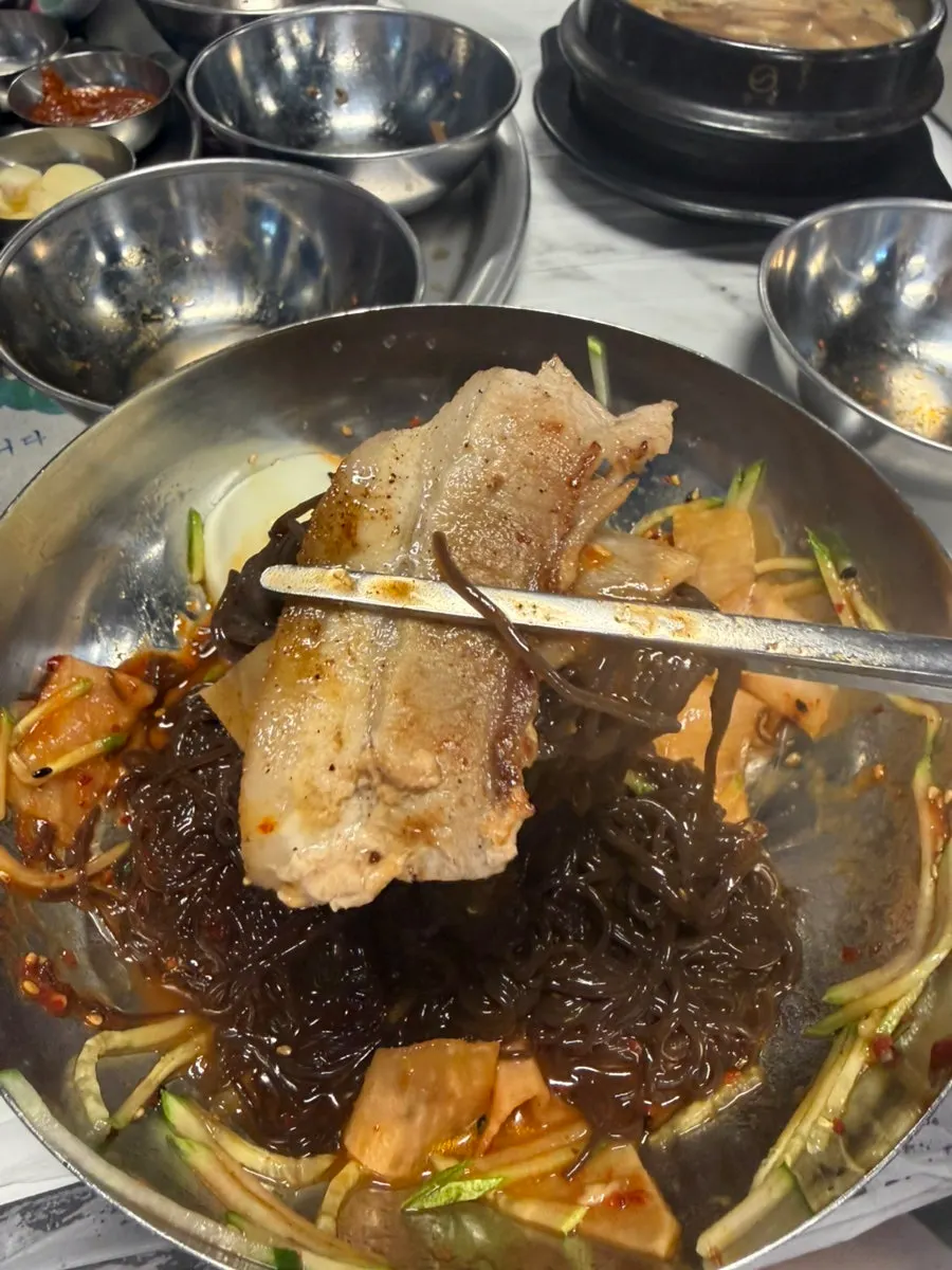 Bibim naengmyeon eaten with frozen pork belly