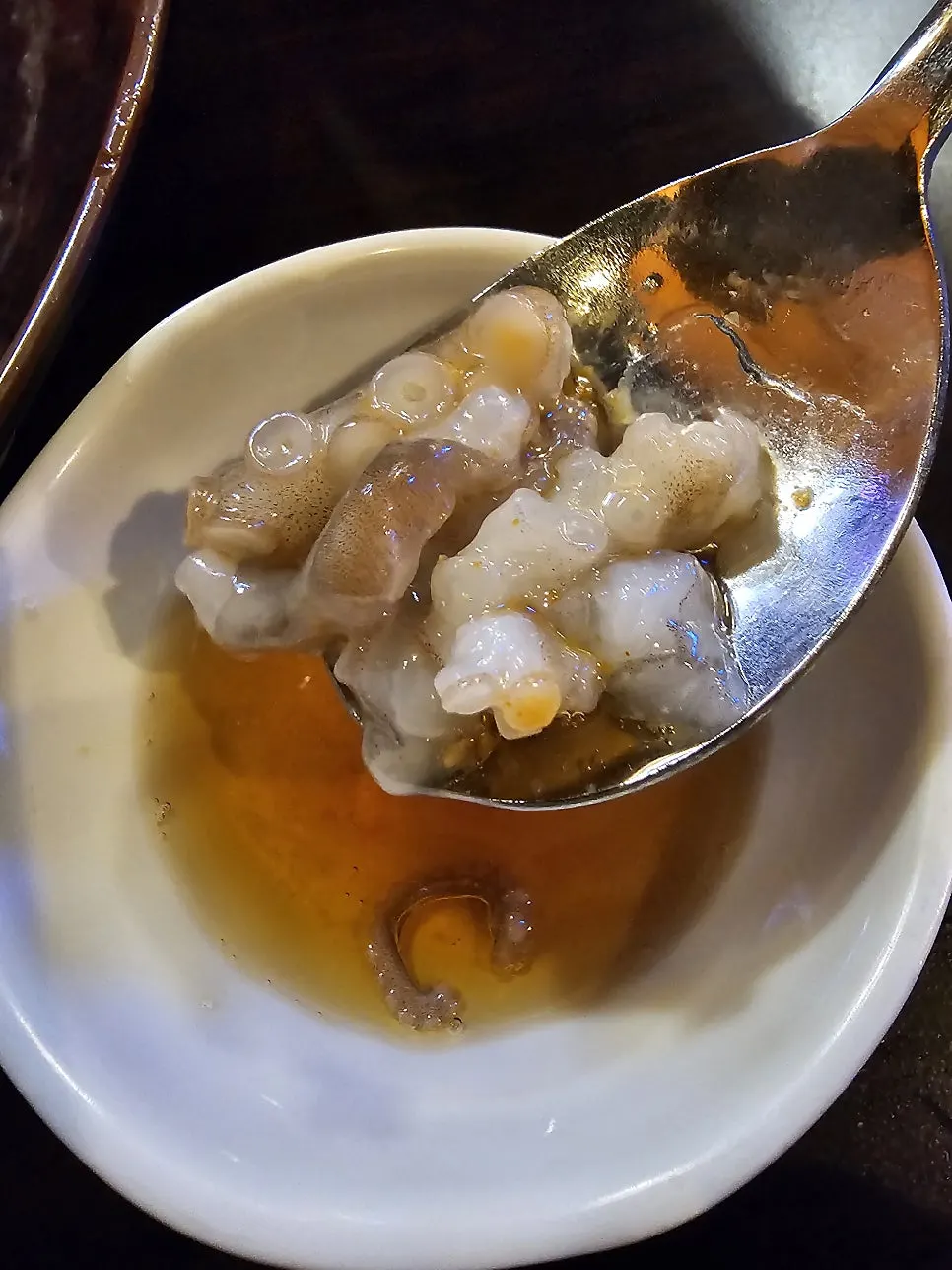 A piece of live octopus dipped in sesame oil sauce