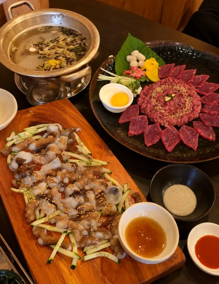 A full spread of Korean beef sashimi, tartare, and live octopus