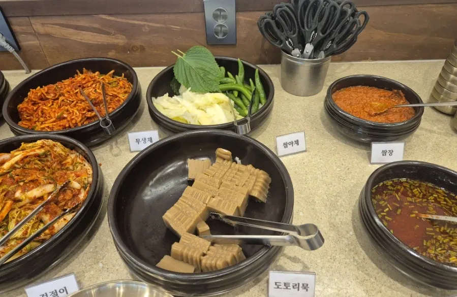 무생채와 도토리묵, 쌈류가 놓인 반찬 셀프바