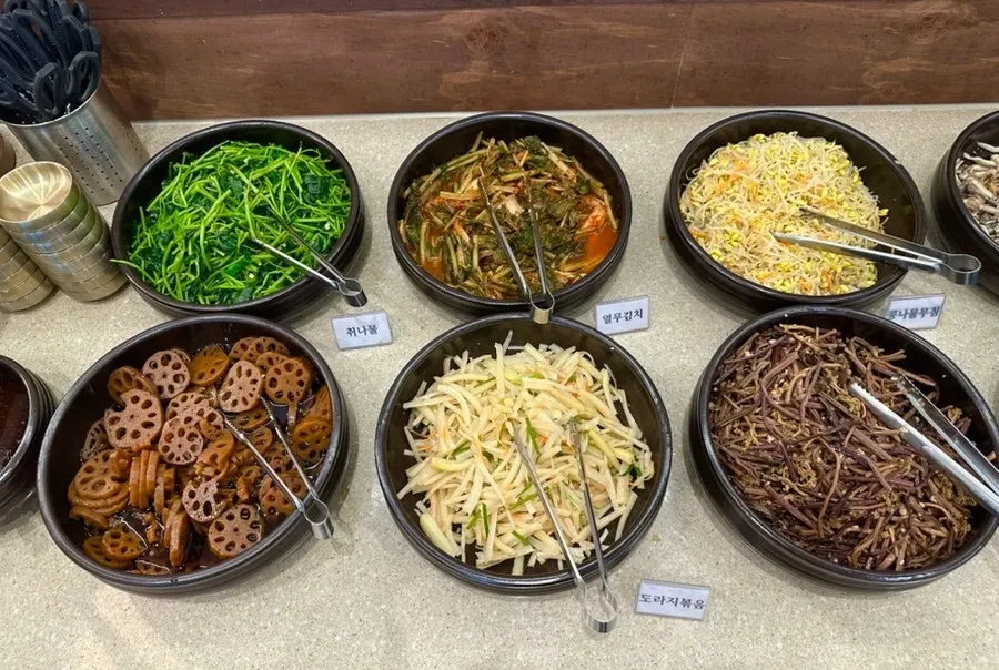 A variety of namul side dishes set out on the self-serve bar