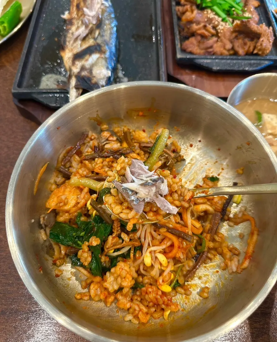 A bite of mixed barley rice with grilled mackerel