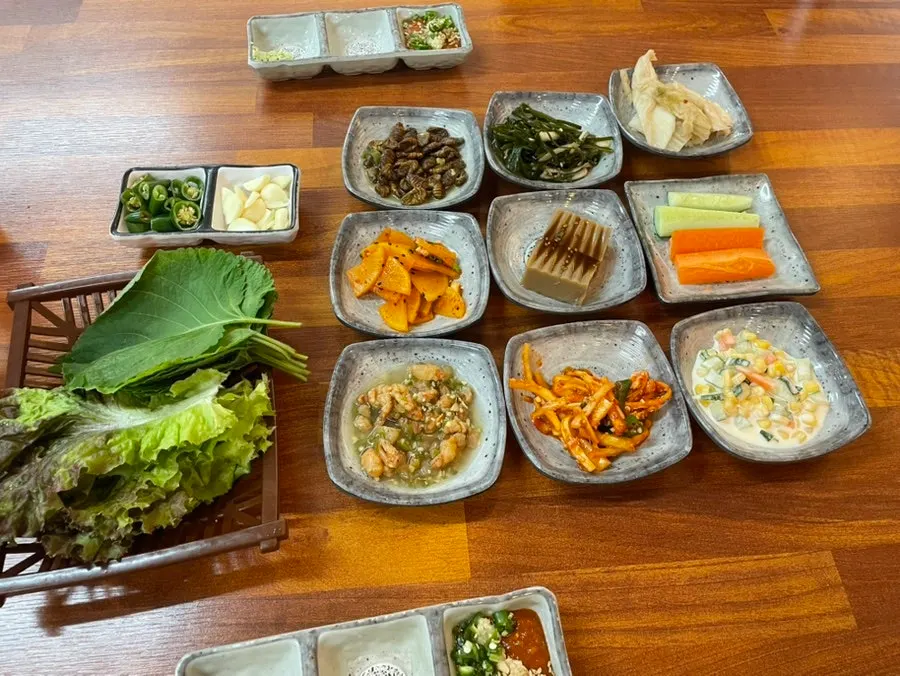 A full spread of side dishes including lettuce wraps and seasoned bellflower root