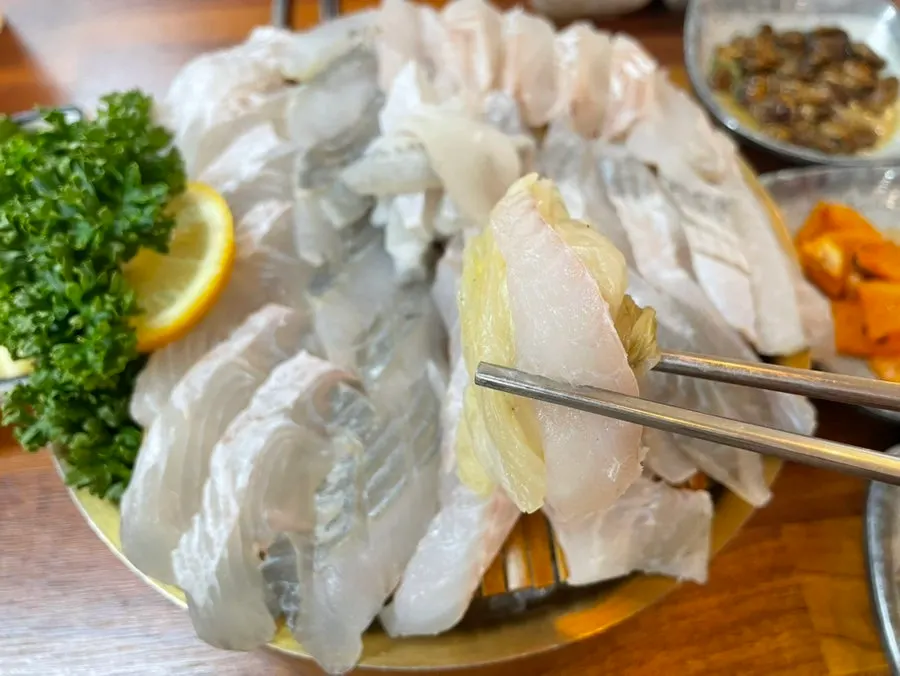 A piece of sashimi placed on white kimchi