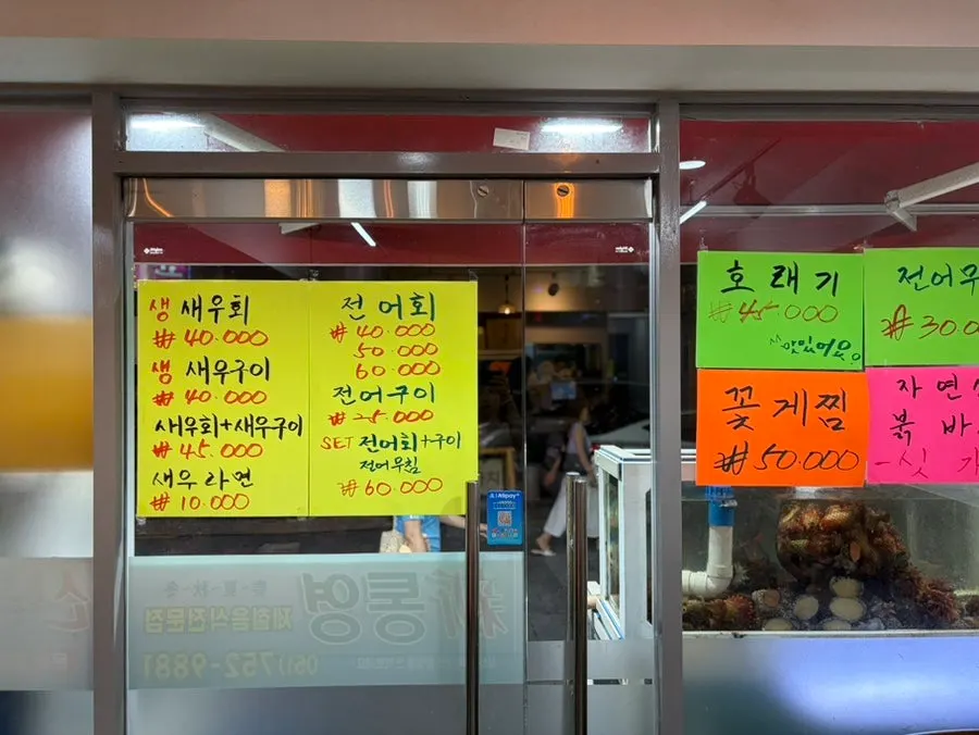 Menu board at Sintongyeong Gul Gukbap showing a variety of sashimi and seafood dishes