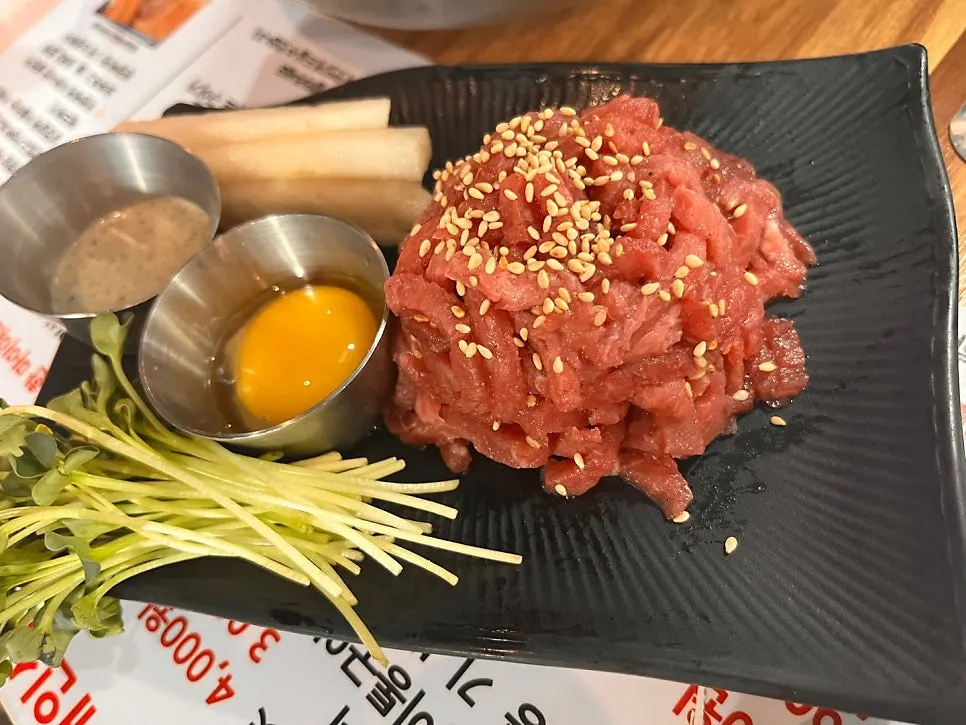 A plate of beef tartare being mixed together