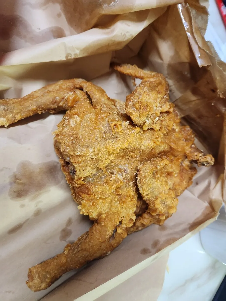 Old-style whole fried chicken unwrapped at home