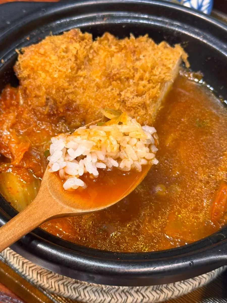 A piece of tonkatsu lifted up together with kimchi