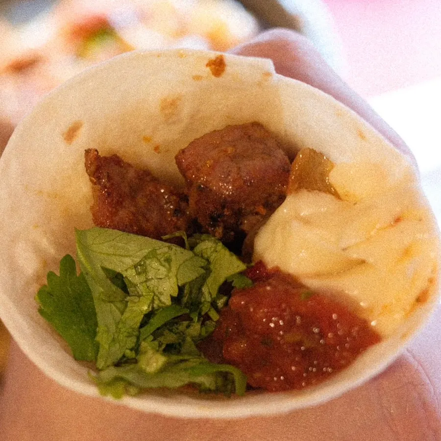 Taco with meat, cilantro, chili sauce and sour cream