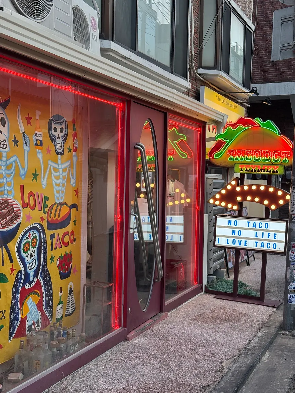 Storefront entrance with a red taco-shaped neon sign