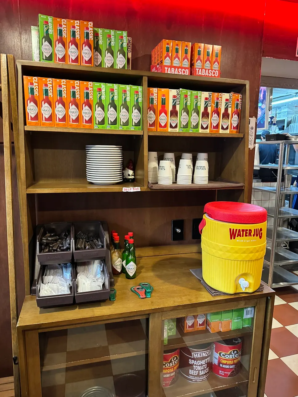 Self-serve bar with small plates, cutlery, and various Tabasco sauces
