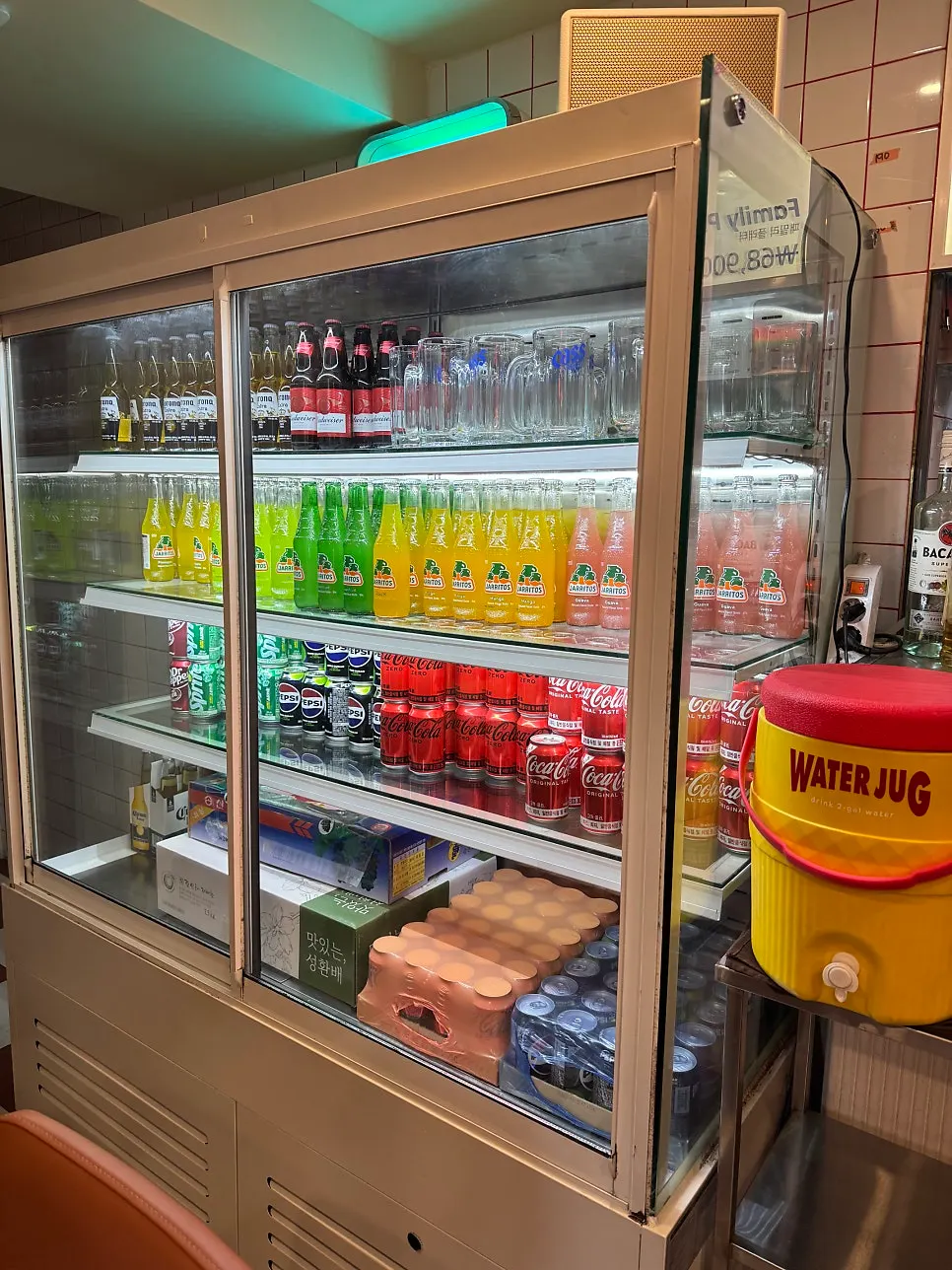 Drink fridge stocked with sodas and colorful Jarritos bottles