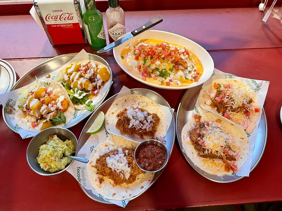 Table spread for two with three tacos and an enchilada