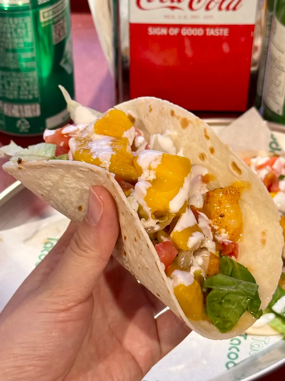 Cross-section of a mango shrimp taco held in one hand