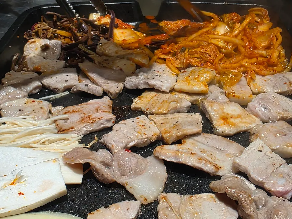Assorted pork cooking on the grill with side ingredients