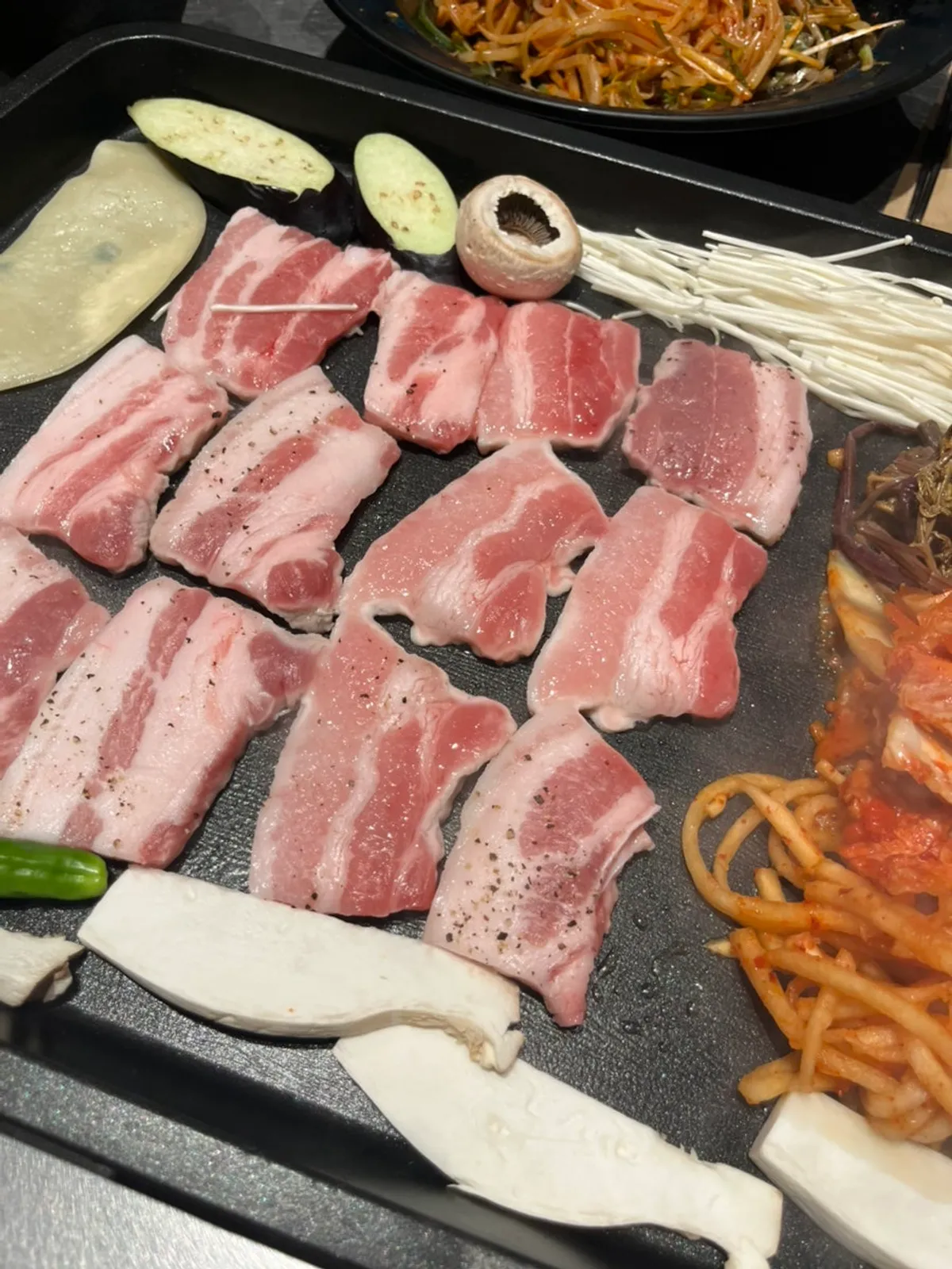 불판 위에서 구워지는 삼겹살과 버섯 모둠