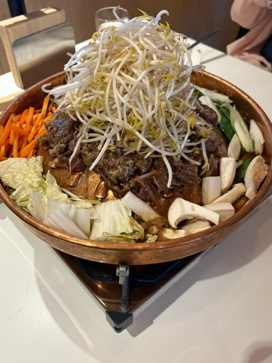 Seoul-style bulgogi with bean sprouts piled on a brass grill pan