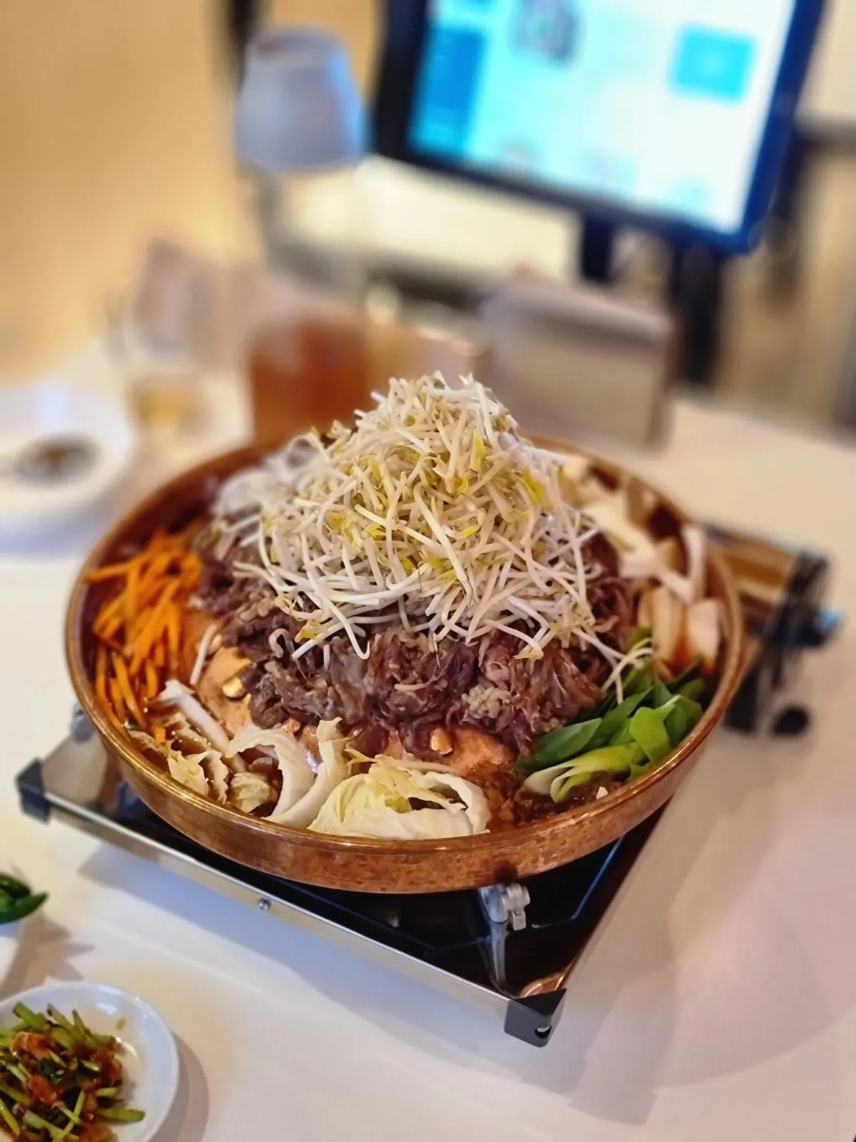 Seoul-style bulgogi and bean sprouts in a brass-toned hot pot