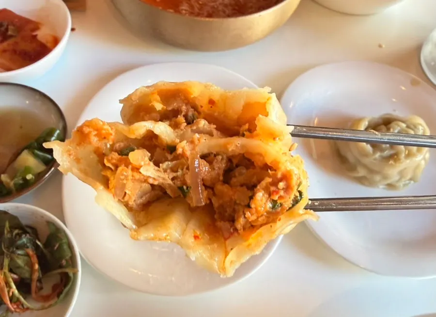 Kimchi and meat dumplings placed side by side on a plate