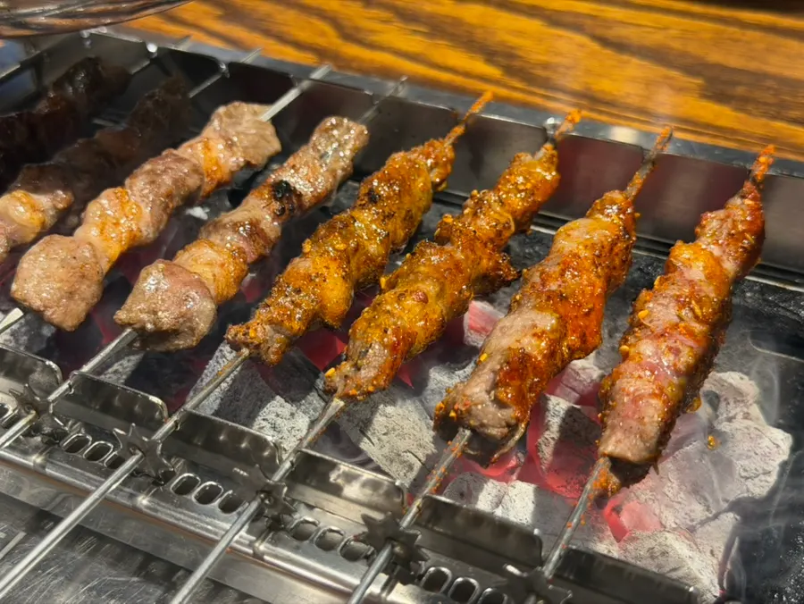 Lamb skewers grilling with dripping fat over charcoal