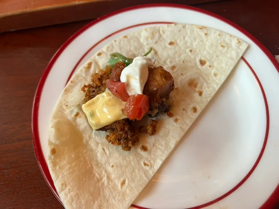 Meat and sauce being loaded onto a tortilla