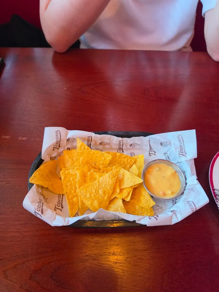 Nachos and warm cheese sauce served as an appetizer