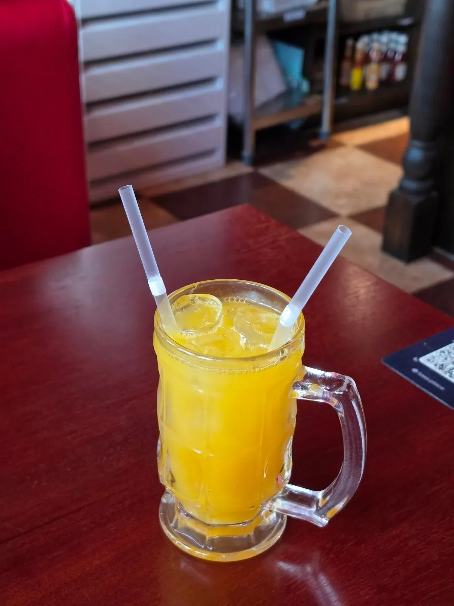 Glass of mango ade on the window-seat table